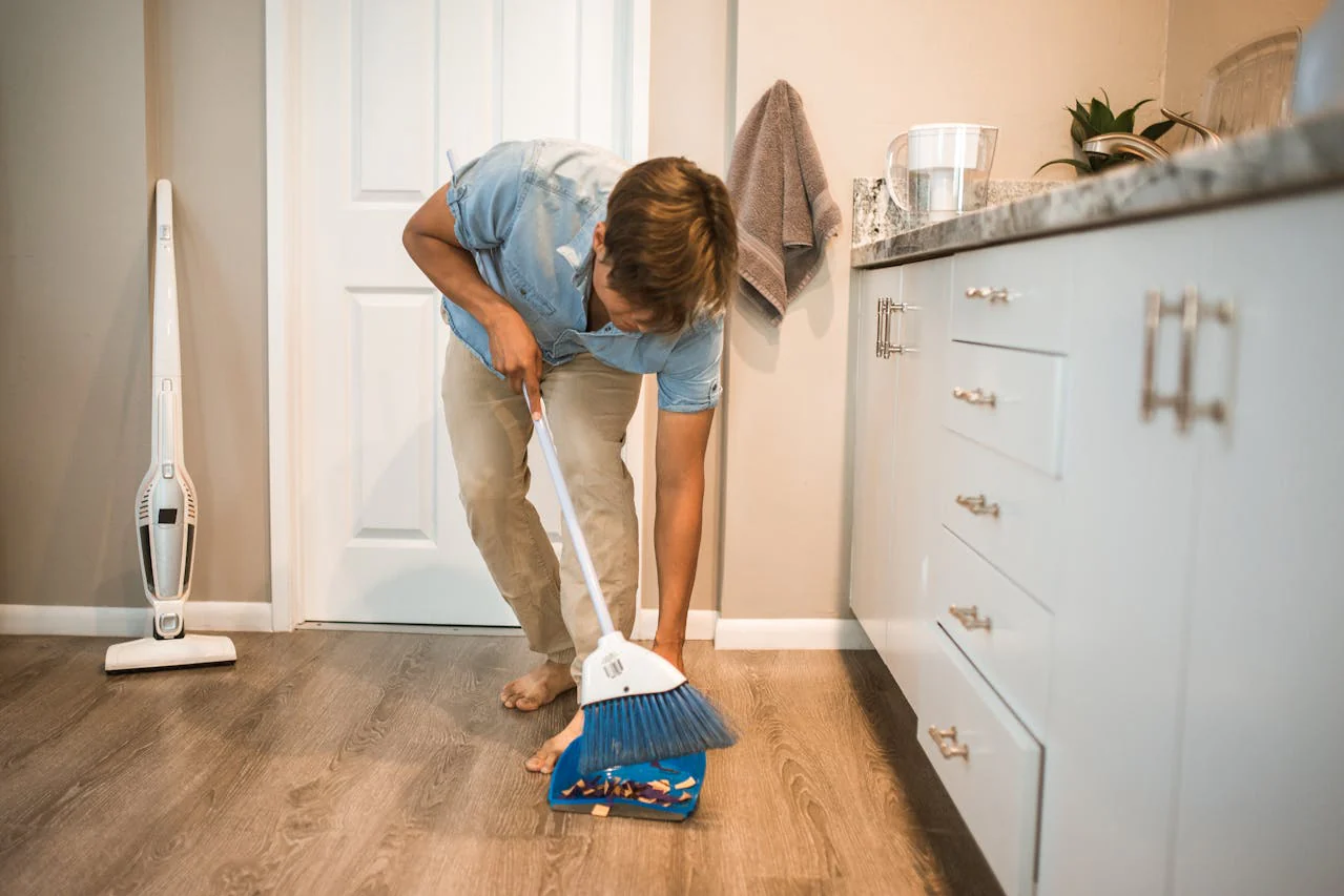man in blue top sweeping the floor